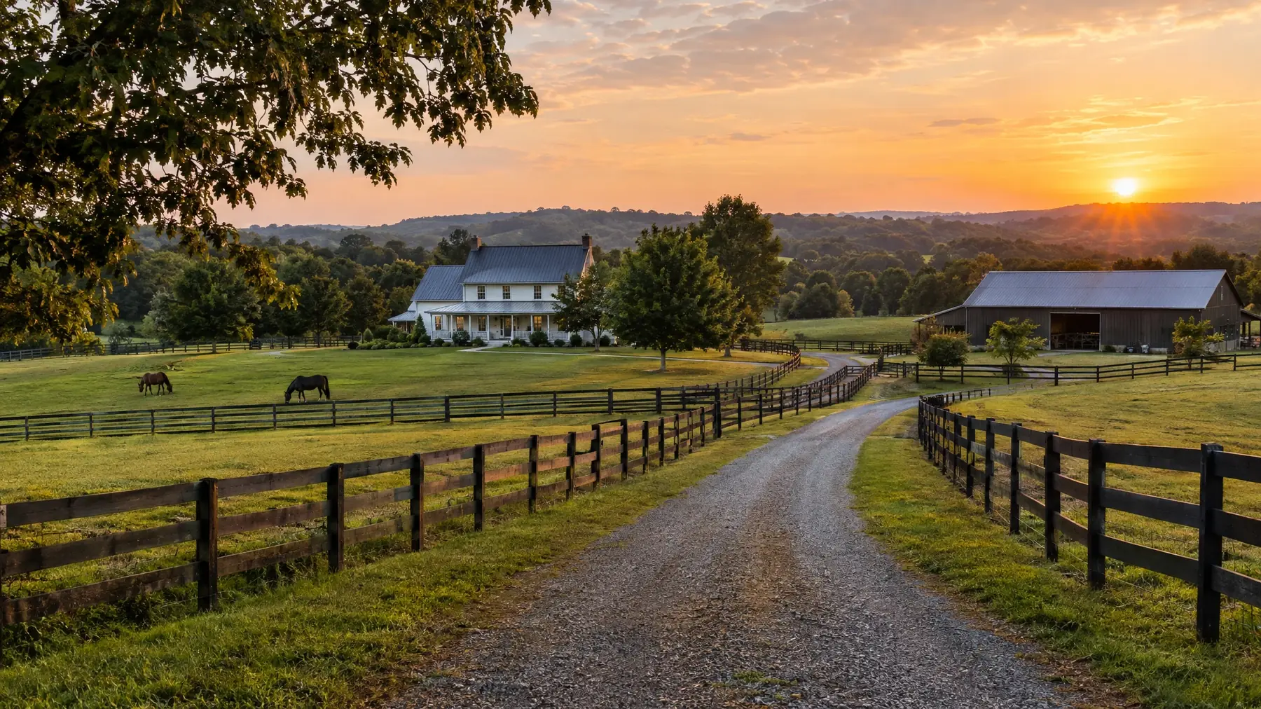 Middle Tennessee farmhouse with a long gravel drive and barn at golden hour
